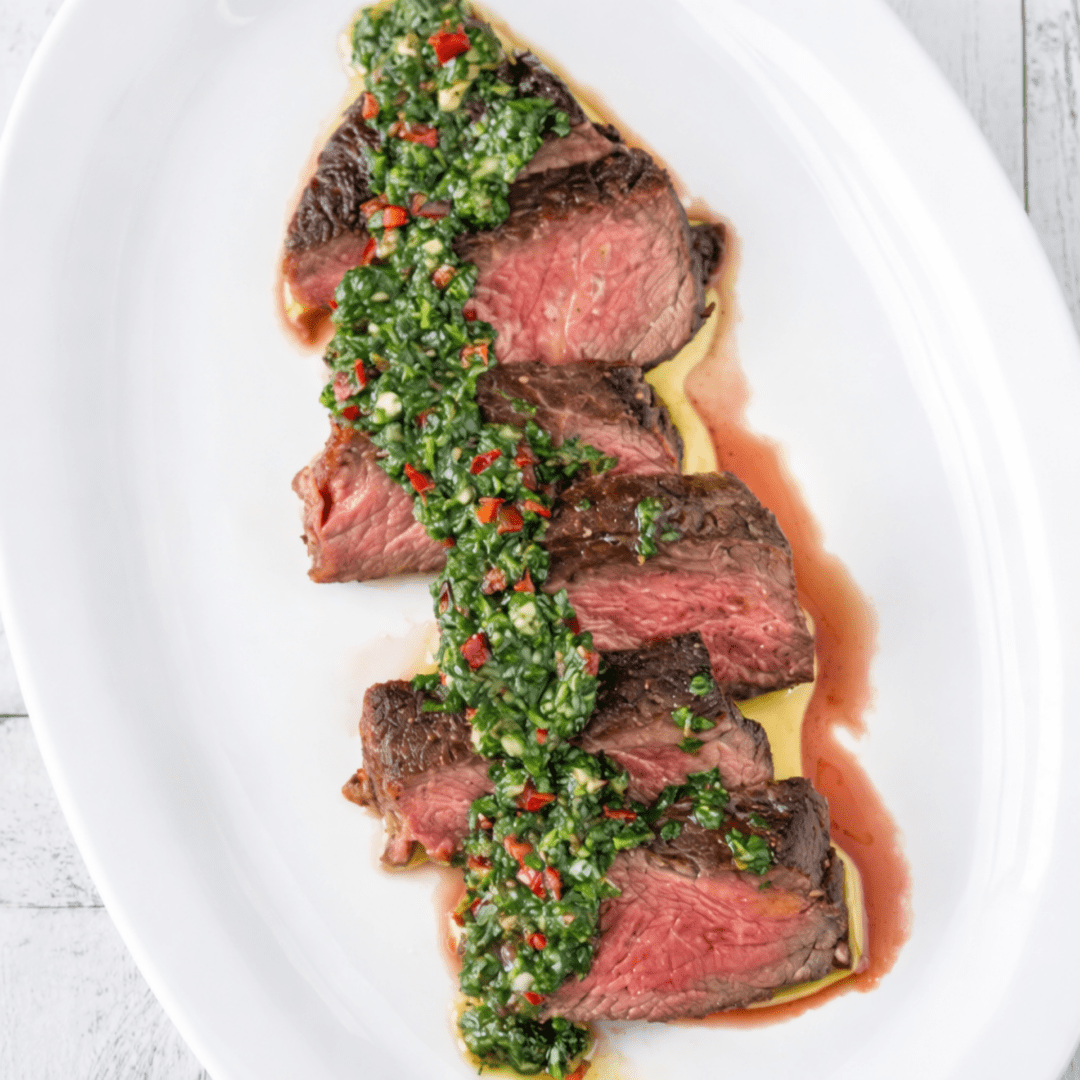 Guests preparing Argentine steak with chimichurri, empanadas, and grilled vegetables during a hands‑on cooking class.