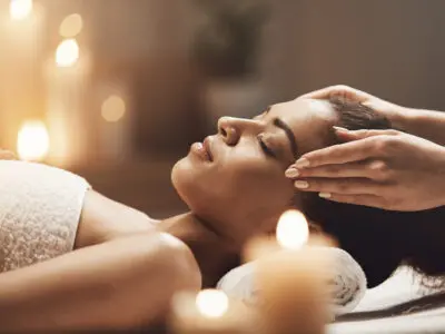 Attractive african girl enjoying face massage in spa salon.