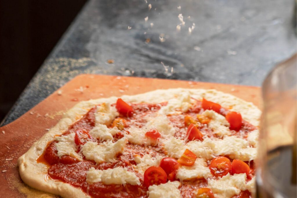 Neapolitan‑style pizza class at The Osthoff Resort with students making dough, sauce, and custom toppings using a pizza stone and peel.