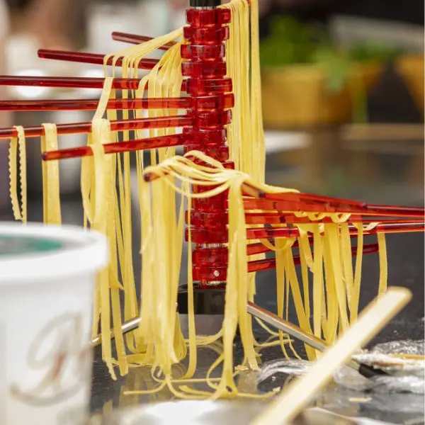 Guests rolling fresh pasta and preparing dishes including Bolognese, creamy Fettuccini Alfredo, and Agnolotti with marinara sauce.