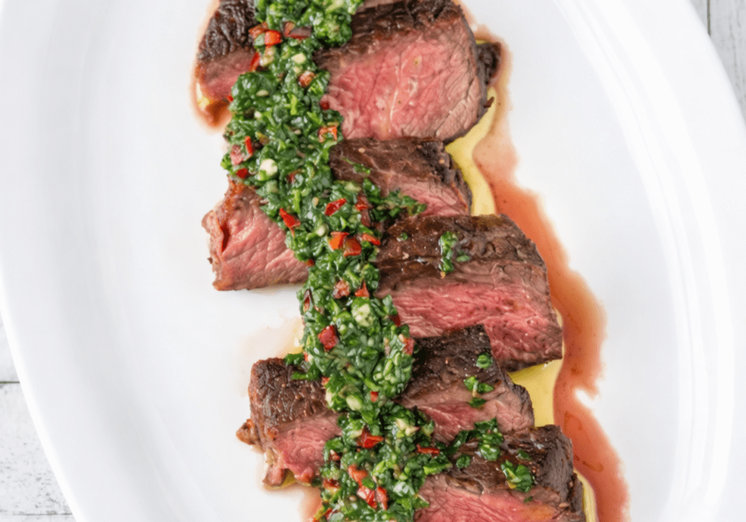Guests preparing Argentine steak with chimichurri, empanadas, and grilled vegetables during a hands‑on cooking class.