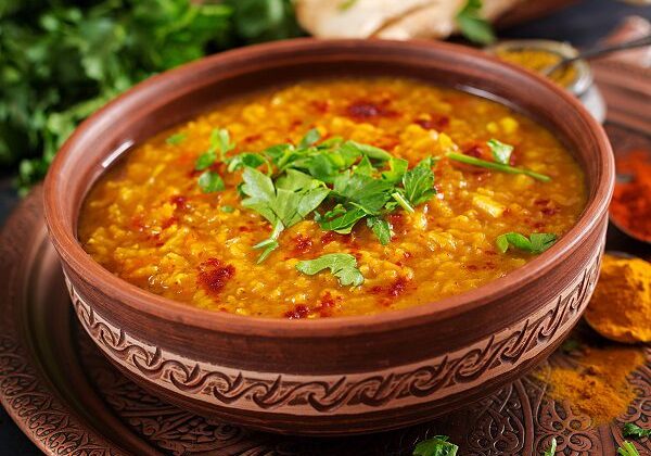 Currie Indian dal. Traditional Indian soup lentils. Indian Dhal spicy curry in bowl, spices, herbs, rustic black wooden background. Authentic Indian dish. Overhead
