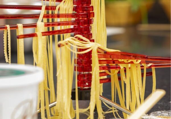 Guests making fresh handmade pasta, shaping fettuccini, farfalle, and agnolotti during an interactive cooking class.