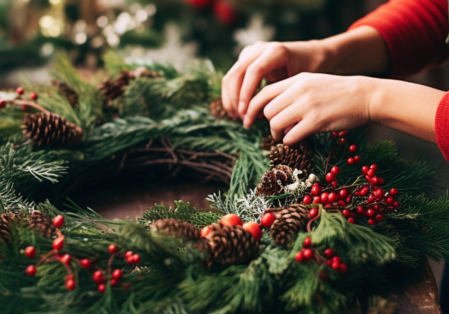 Guest creating a 24‑inch holiday wreath with festive greenery, ribbon, and seasonal décor at The Osthoff Resort