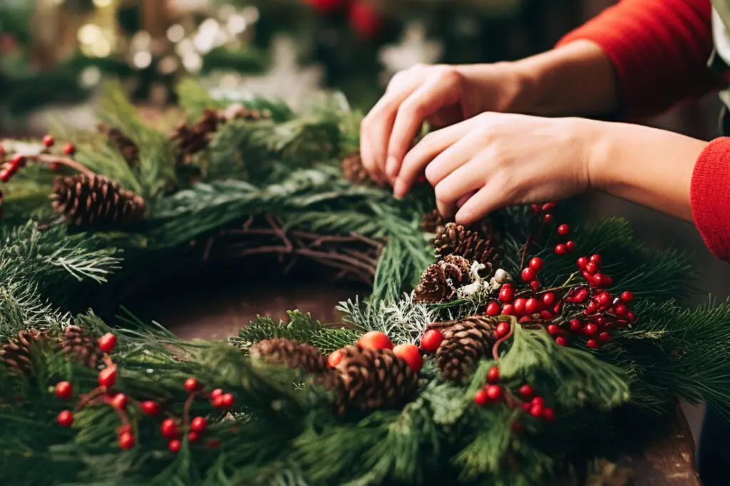 Guest creating a 24‑inch holiday wreath with festive greenery, ribbon, and seasonal décor at The Osthoff Resort