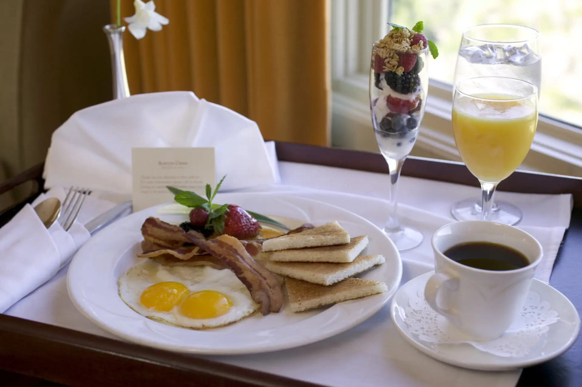 Room service breakfast at The Osthoff Resort featuring pastries, bacon, and a glass of orange juice.